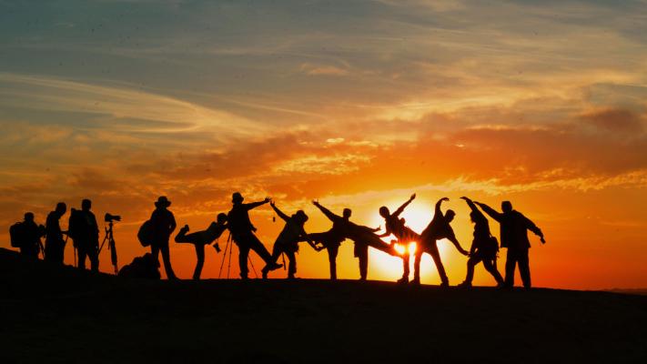Photo showing silhouettes of a team of people in front of a sunset